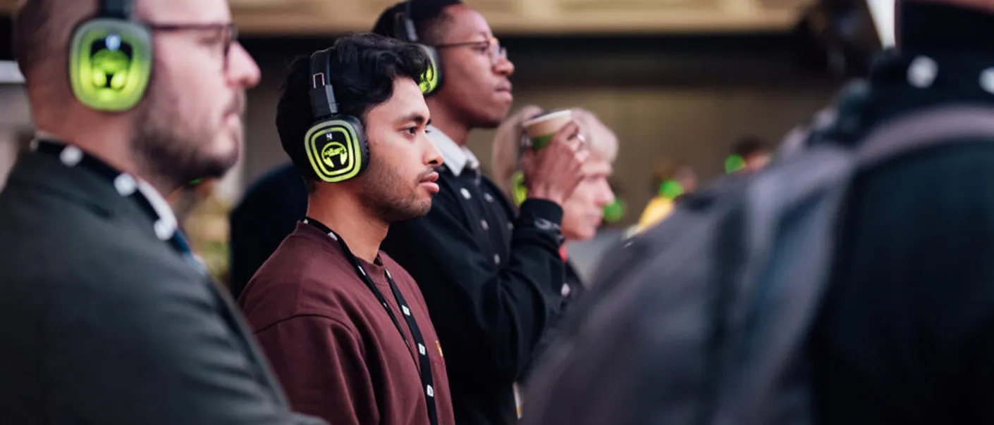 Asistentes a un evento de empresa escuchando con auriculares verdes