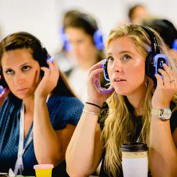 Dos asistentes ajustando sus auriculares de traducción simultánea