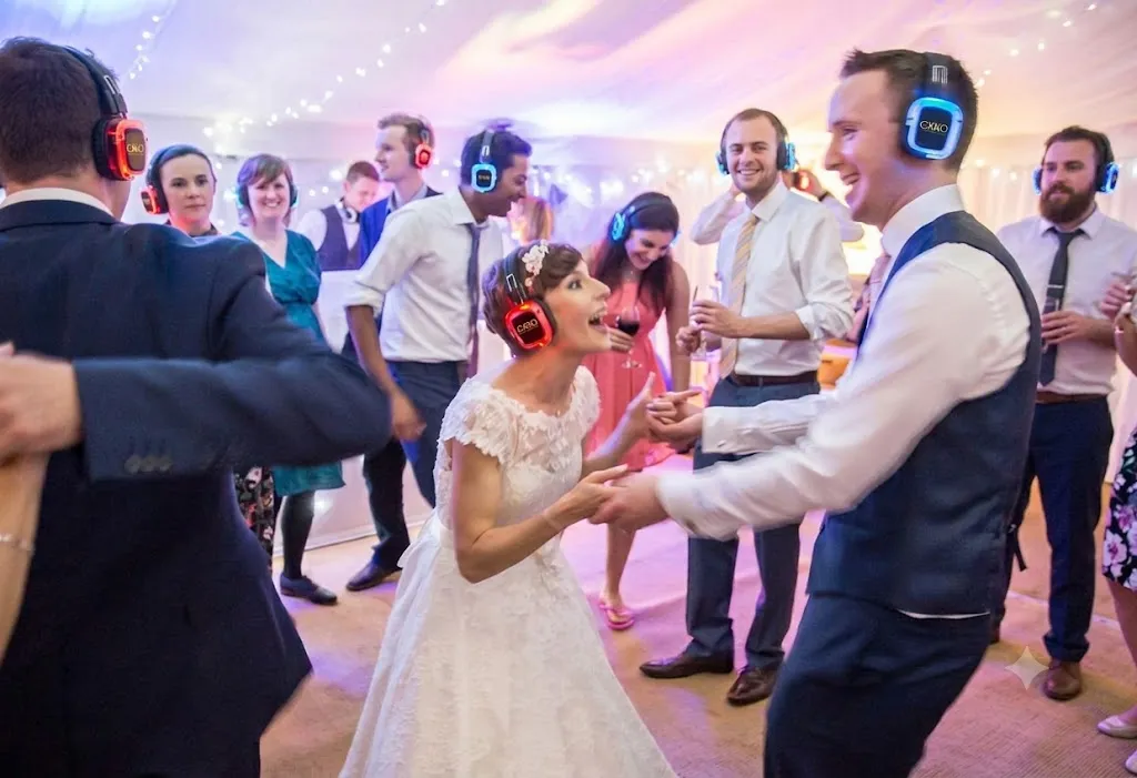 Invitados y novios bailando con cascos inalámbricos en una boda