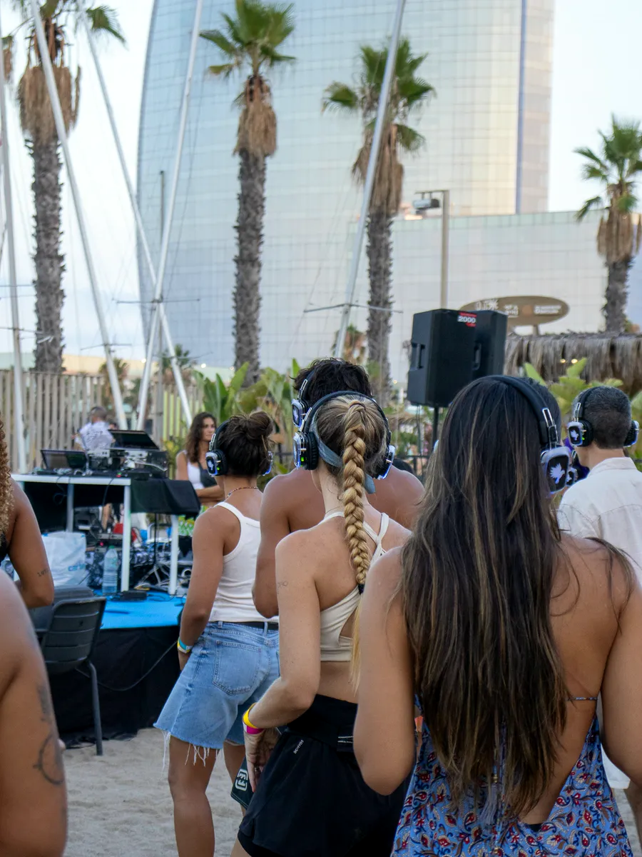 Público con auriculares frente a la cabina del DJ en la playa