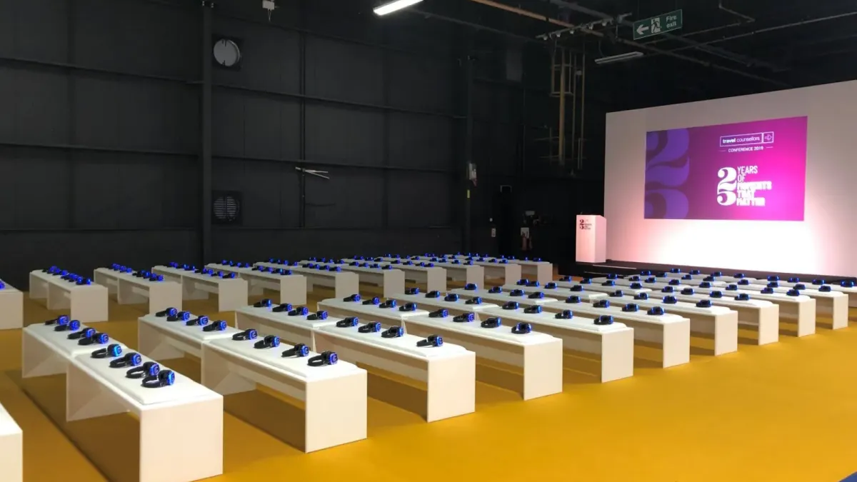Auditorio de feria con bancos y auriculares preparados frente al escenario