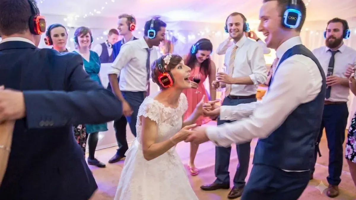 Invitados y novios bailando con cascos inalámbricos en una boda