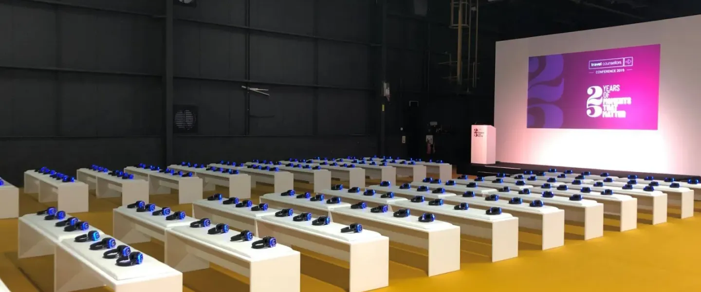 Auditorio de feria con bancos y auriculares preparados frente al escenario