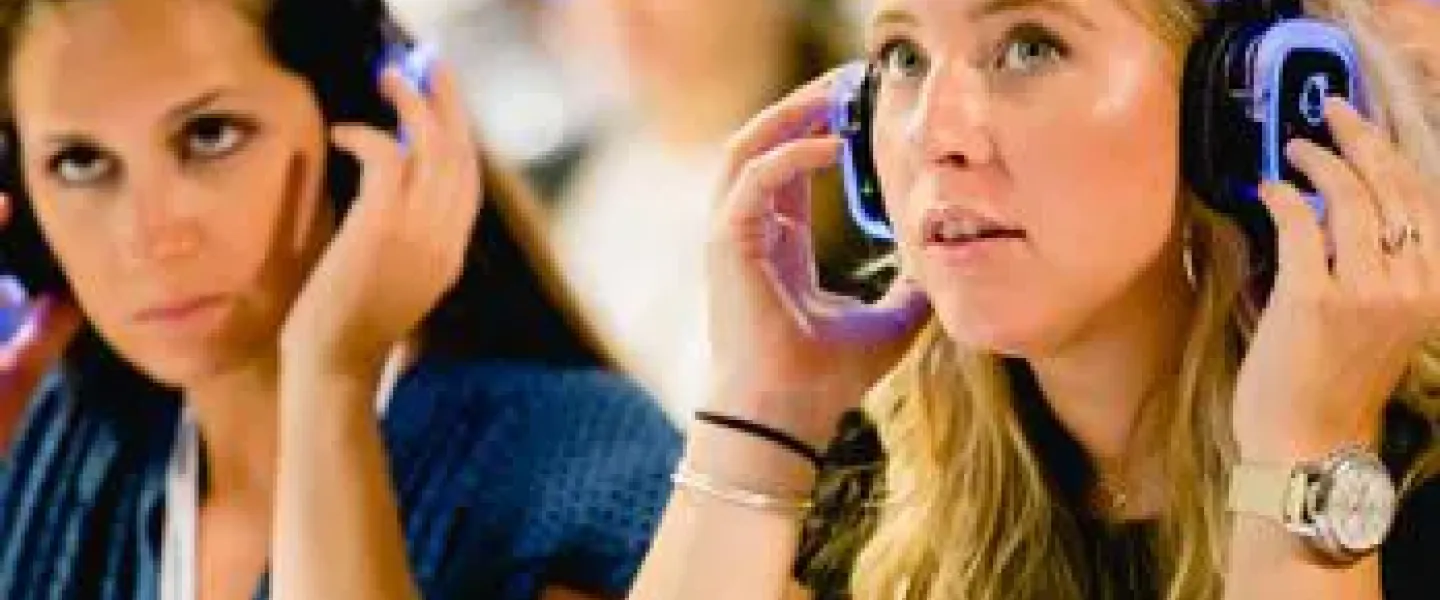Dos asistentes ajustando sus auriculares de traducción simultánea