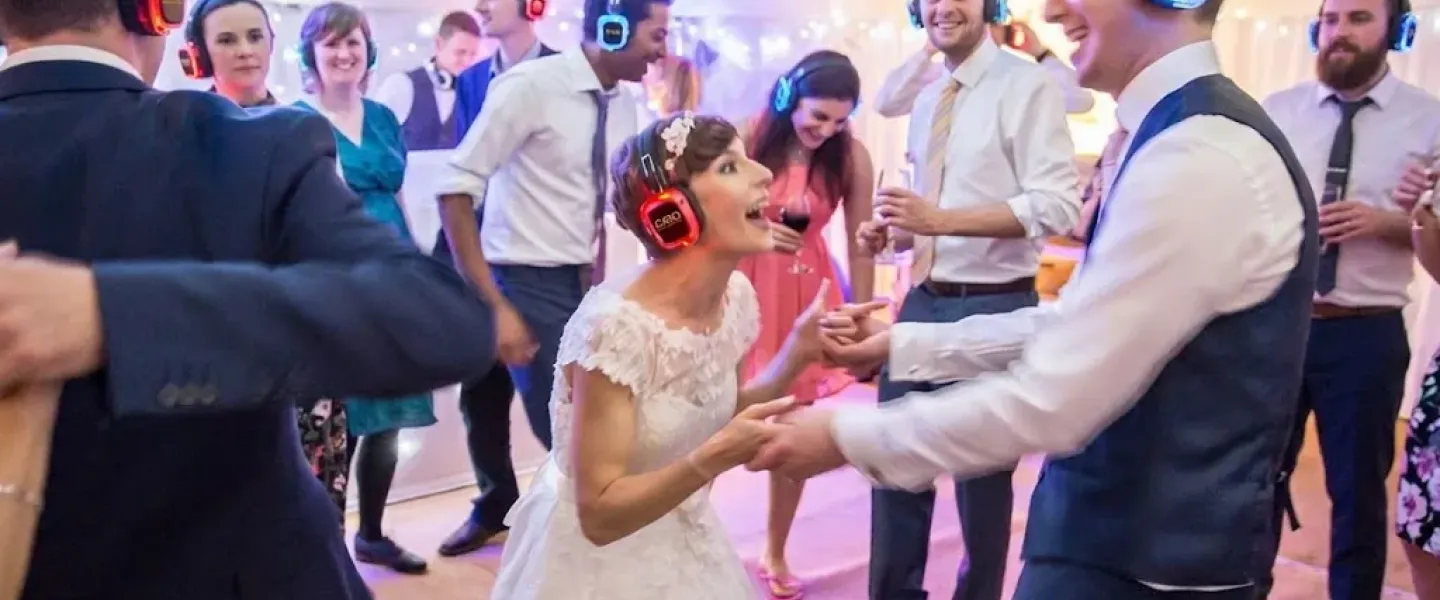 Invitados y novios bailando con cascos inalámbricos en una boda