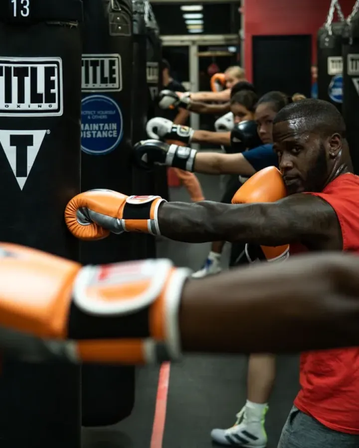Grupo entrenando boxeo con sacos en una clase para empresas