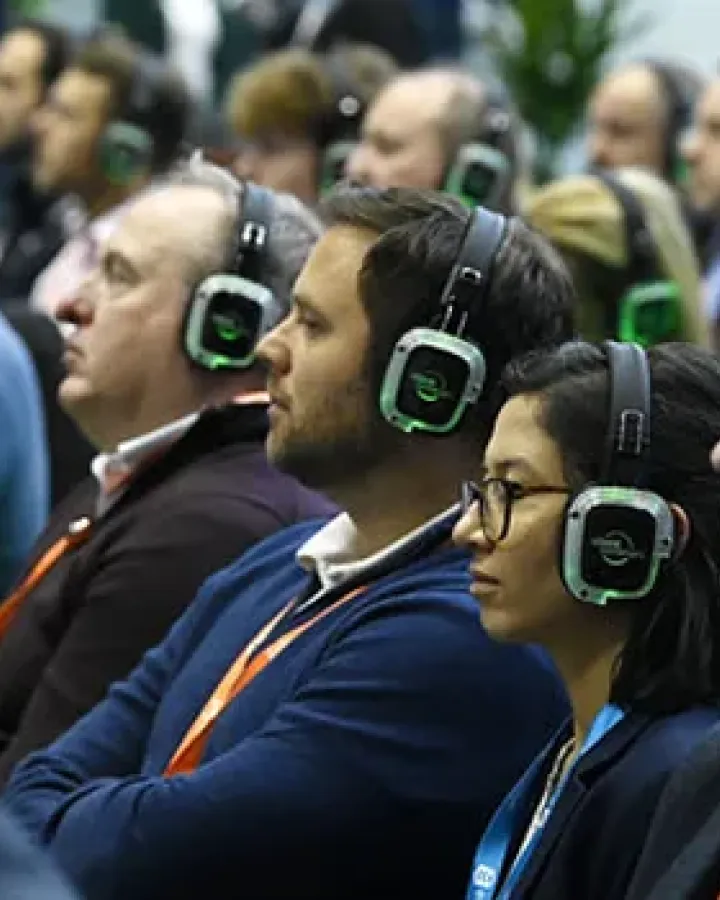 Directivos siguiendo una ponencia con auriculares inalámbricos