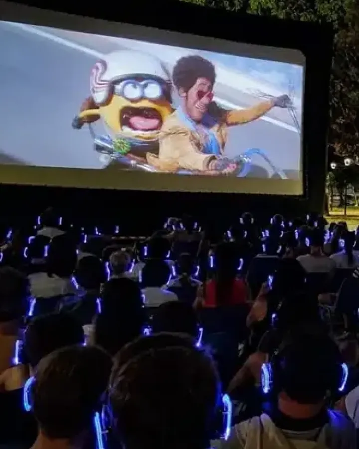Cine al aire libre con público usando auriculares inalámbricos