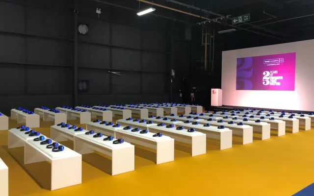 Auditorio de feria con bancos y auriculares preparados frente al escenario