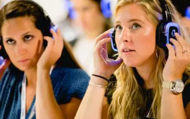 Dos asistentes ajustando sus auriculares de traducción simultánea