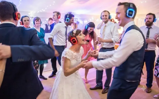 Invitados y novios bailando con cascos inalámbricos en una boda