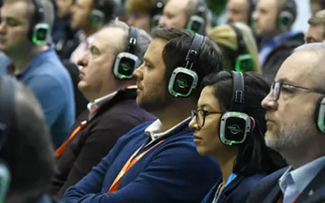 Directivos siguiendo una ponencia con auriculares inalámbricos
