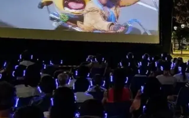 Cine al aire libre con público usando auriculares inalámbricos